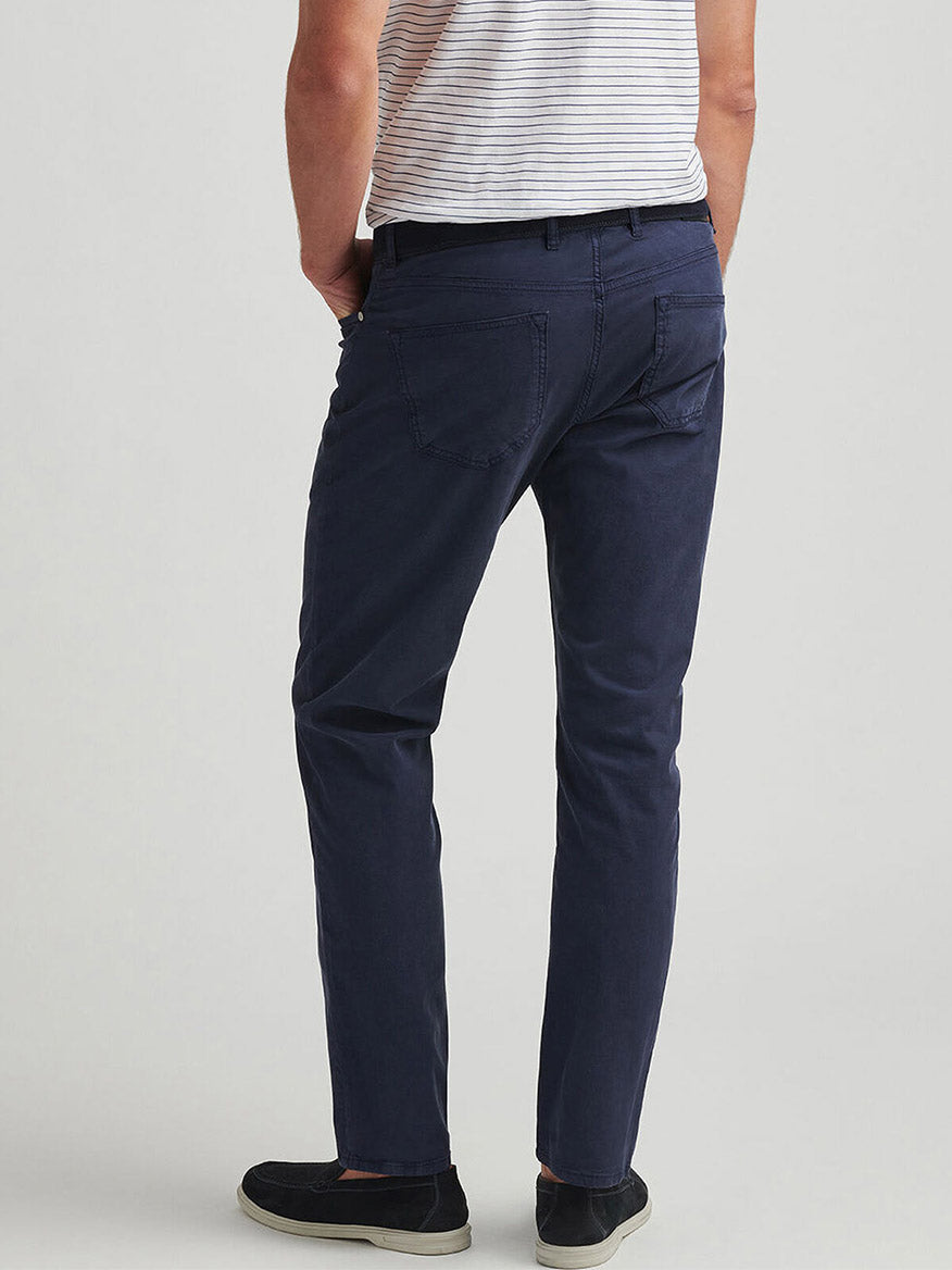 A person is shown from the back wearing a white striped t-shirt, black shoes, and Peter Millar Wayfare Five-Pocket Pant in Navy, standing against a plain light background.