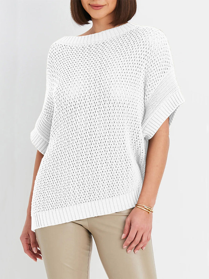 A woman stands with her arms relaxed at her sides, wearing the Planet by Lauren G Crochet Popover in White and beige pants—a look that exudes effortless bohemian sophistication.