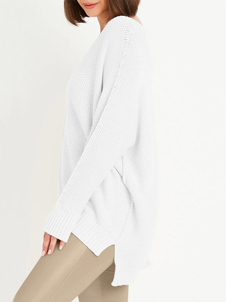 A woman in a relaxed luxury outfit, wearing a Planet by Lauren G Pebble V-Neck Sweater in white and beige pants, standing sideways against a plain background.