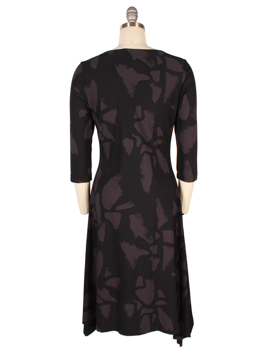 The Porto Risa Dress in Mulberry Palermo features 3/4 sleeves, an abstract dark gray pattern on black fabric, and an asymmetrical hem, shown from the back on a dress form. Made in Italy.
