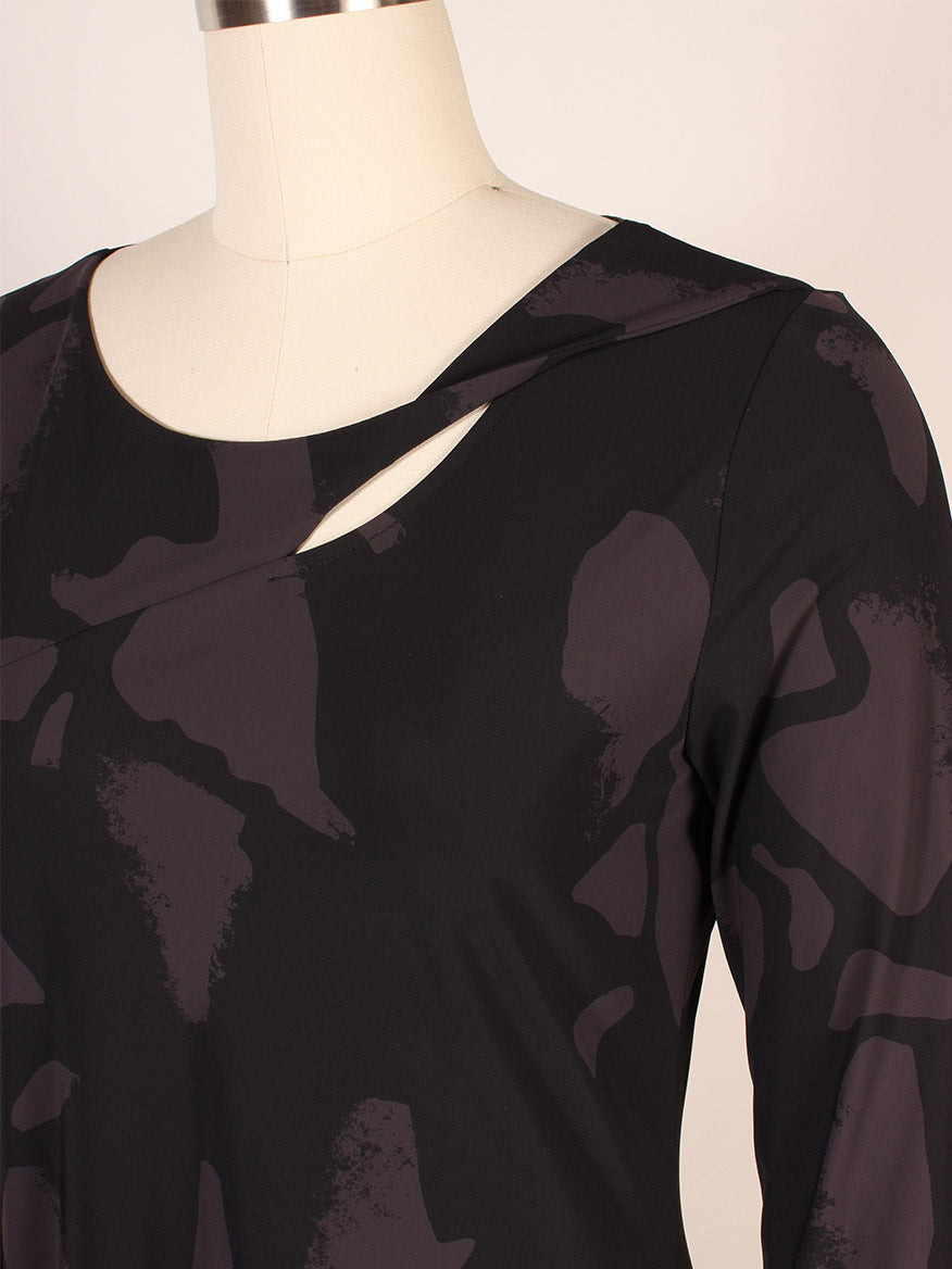A mannequin displays the Porto Risa Dress in Mulberry Palermo, a long-sleeve dress with abstract dark patterns and an asymmetrical neckline featuring a small cutout, crafted in Italy for modern elegance.
