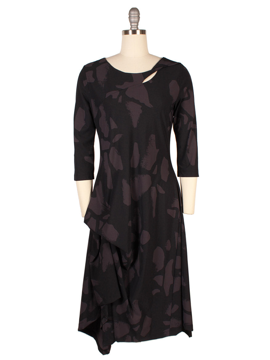 The Porto Risa Dress in Mulberry Palermo is an Italian-made asymmetrical dress with 3/4 sleeves and abstract dark patterns, shown on a mannequin.