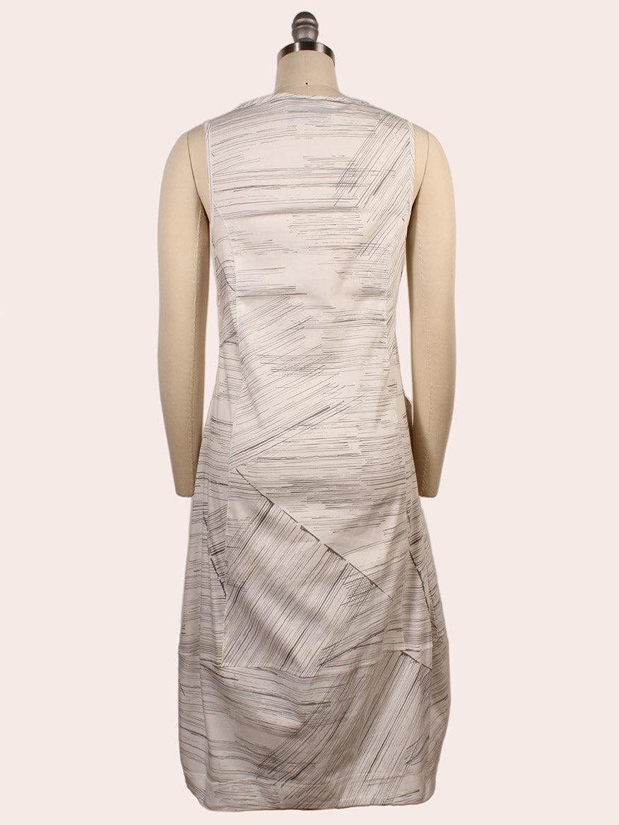 The Porto Santiago Sleeveless Dress in Quail Laguna is shown from the back, with a light beige abstract linear pattern and classic boat neckline. This knee-length dress offers effortless Italian elegance.