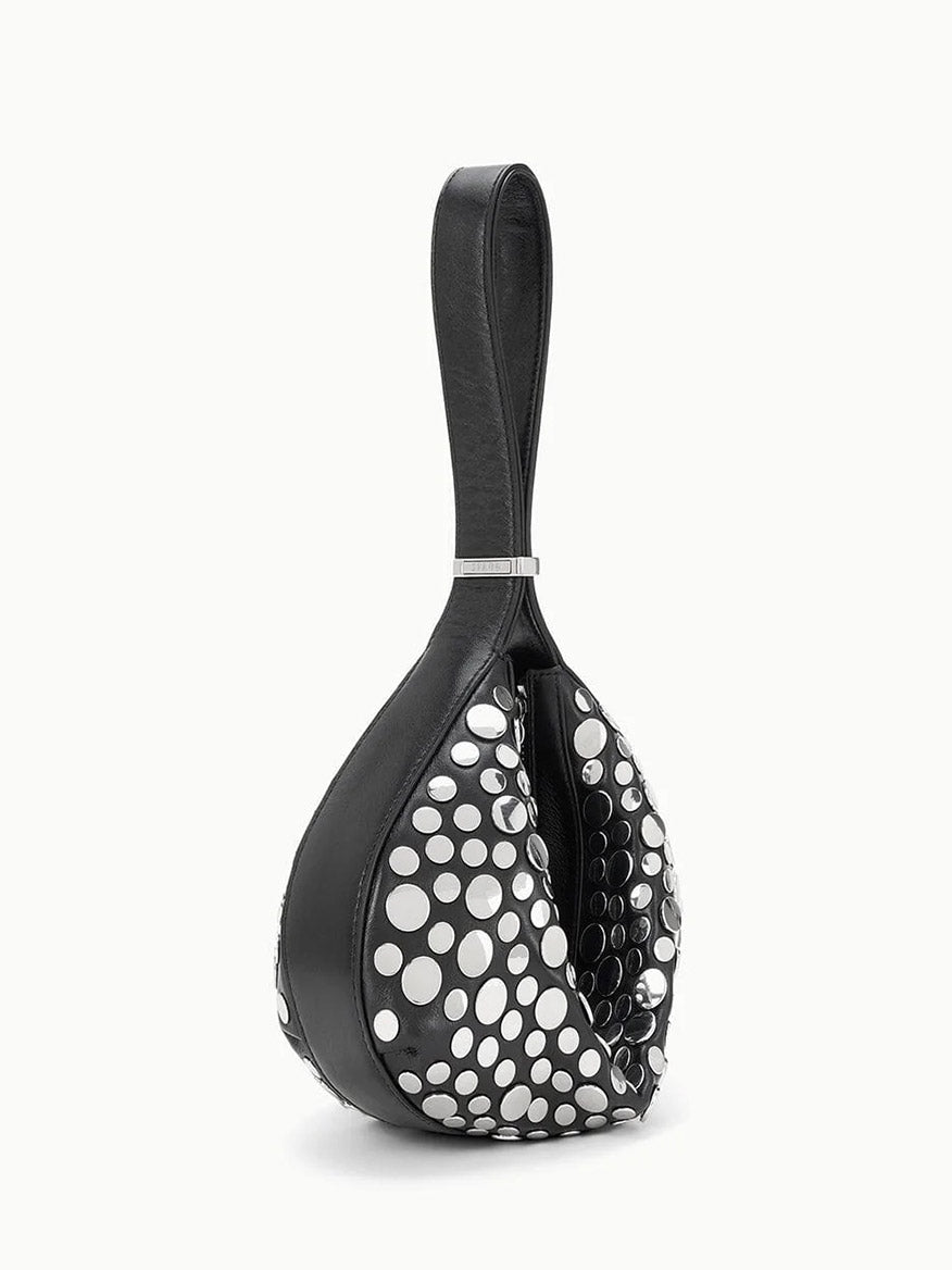 The STAUD Demy Shoulder Bag in Rivets is a black, teardrop-shaped shoulder bag with a looped handle and large white polka dots, crafted from soft nappa leather.