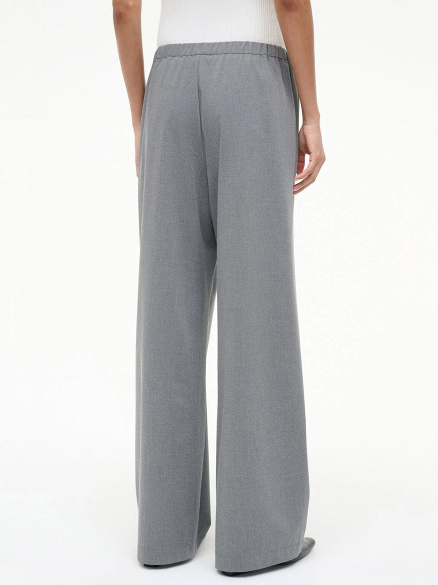 A person wears the STAUD Denali Pant in Static (wide-leg gray), styled with a white top, facing away with hands at their sides against a plain light background.