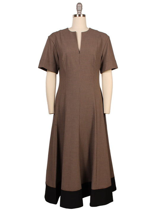 The STAUD Frances Short Sleeve Dress in Houndstooth features a split neck, short sleeves, a mid-length A-line skirt, and black trim at the hem, displayed on a dress form.