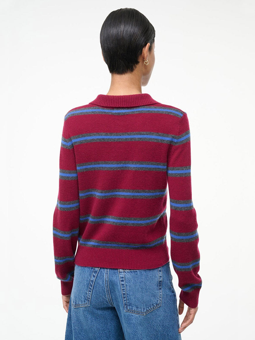 Person with short dark hair wearing the STAUD Gemma Cashmere Sweater in Crimson Stripe and blue jeans, shown from the back against a plain white background.