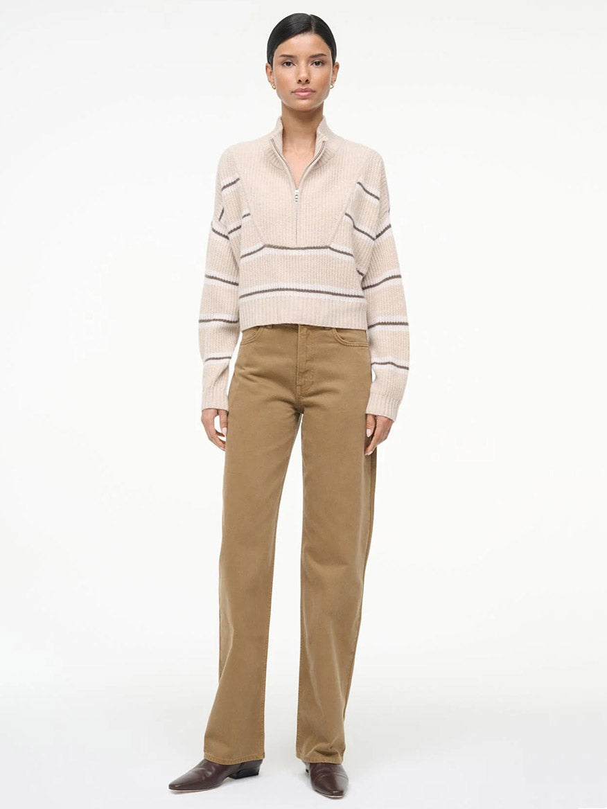 A person stands against a plain background wearing the STAUD Hampton Cropped Cashmere Sweater in Whisper Stripe, paired with tan wide-leg pants and brown shoes.