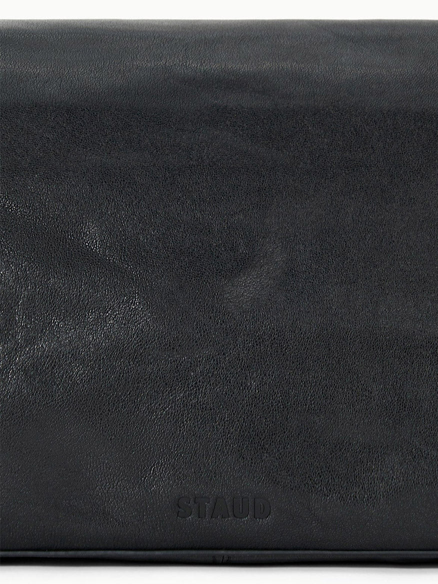 Close-up of the smooth black leather surface of the STAUD Harlow Medium Bag in Black, featuring the embossed "STAUD" logo at the bottom center.