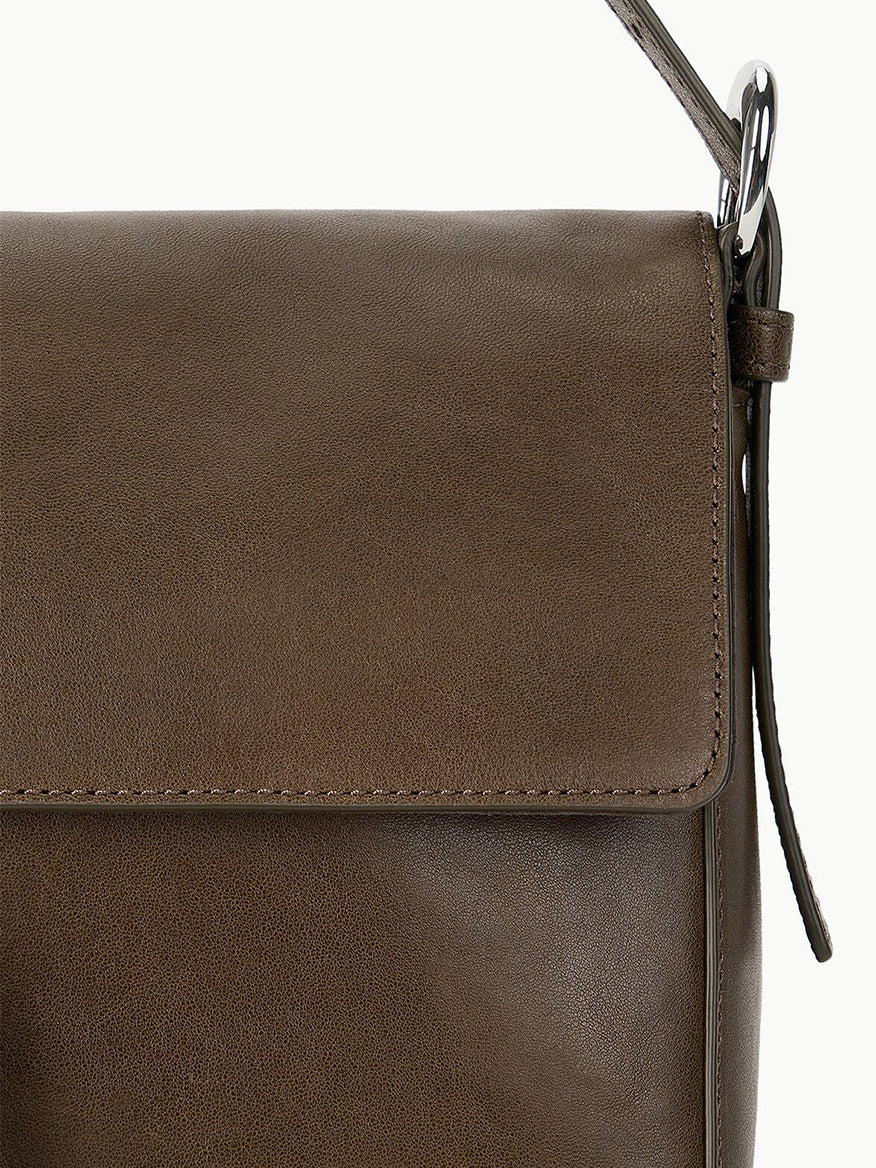 Close-up of the STAUD Harlow Medium Bag in Truffle, a brown leather shoulder bag featuring a flap closure, visible stitching, and an elegant Moon buckle.