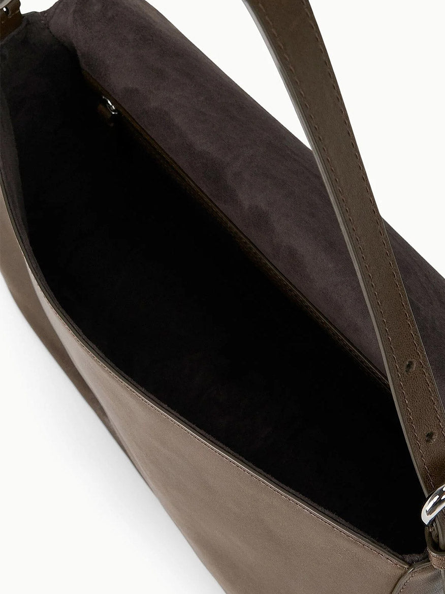 A close-up of the STAUD Harlow Medium Bag in Truffle shows its open brown leather design, dark interior, adjustable strap, and elegant Moon buckle.