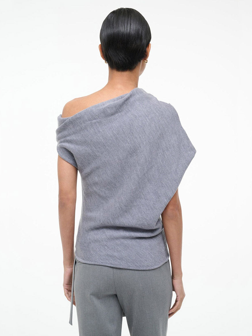 A person stands with their back to the camera, wearing the STAUD Mabel Sweater in Heather Grey and grey pants, set against a plain white background.