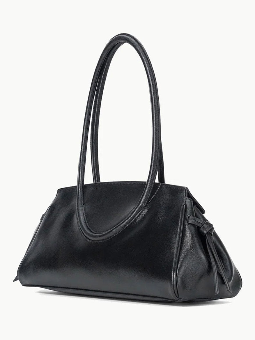 The STAUD Maude Shoulder Bag in Black features polished leather, double loop handles, a side knot detail, and an elegant east-west silhouette, shown against a plain white background.