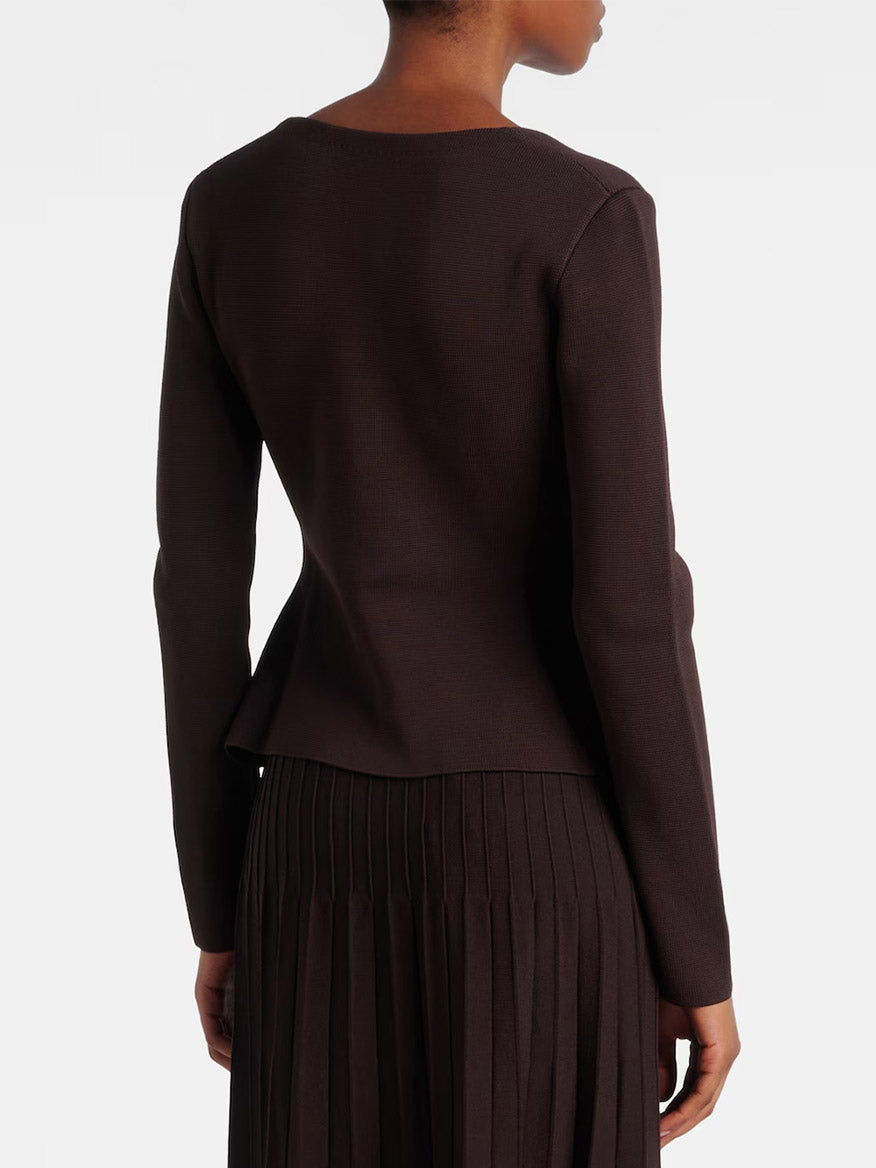 A person is shown from the back wearing the STAUD Rachela Sweater in Earth, a long-sleeved dark brown knit top with a notched square neck, paired with a matching pleated skirt against a plain background.