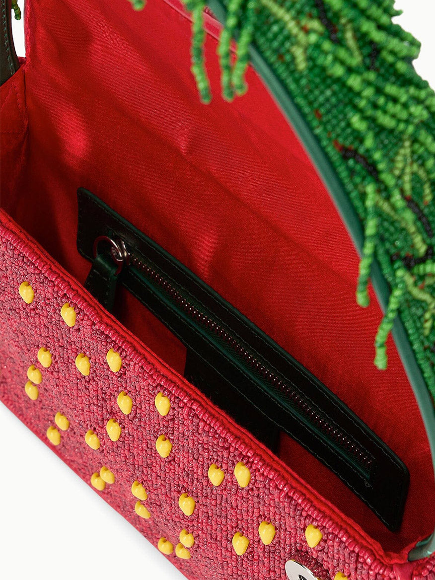 The STAUD Tommy Beaded Bag in Strawberry Dream features an open red beaded design with yellow accents, a green beaded handle, and a visible black zippered pocket inside.