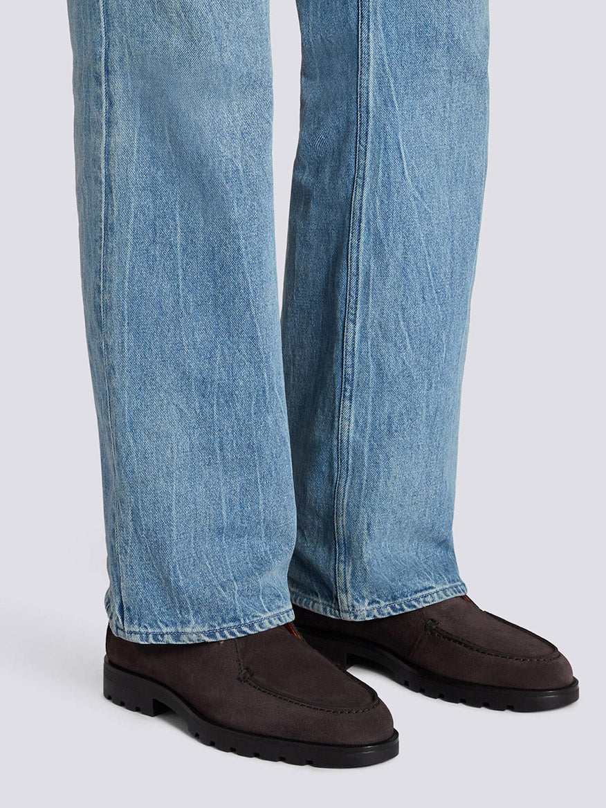 A person wearing light blue jeans and Santoni Desert Lace Up Boot in Grey Suede stands on a light gray surface.