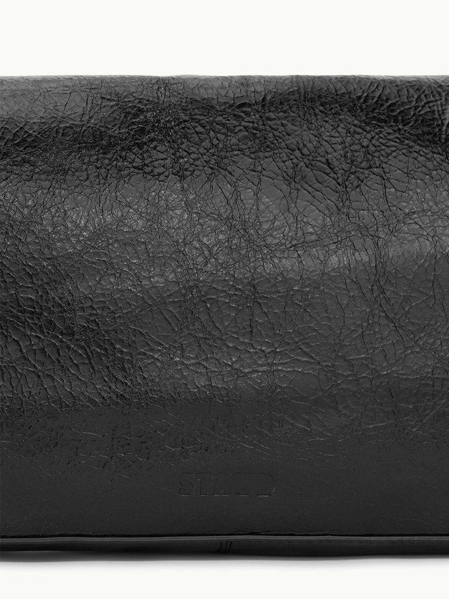 Close-up of the STAUD Harlow Bag in Black, featuring textured crinkle leather and the brand name "STAUD" subtly embossed near the bottom center.