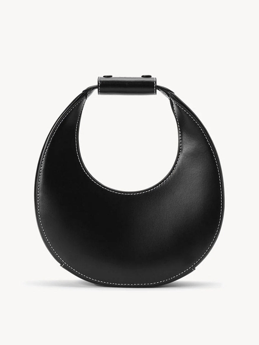 The STAUD Mini Moon Bag in Black is a leather crescent bag with white stitching, a rounded body, and a short, wide top handle.
