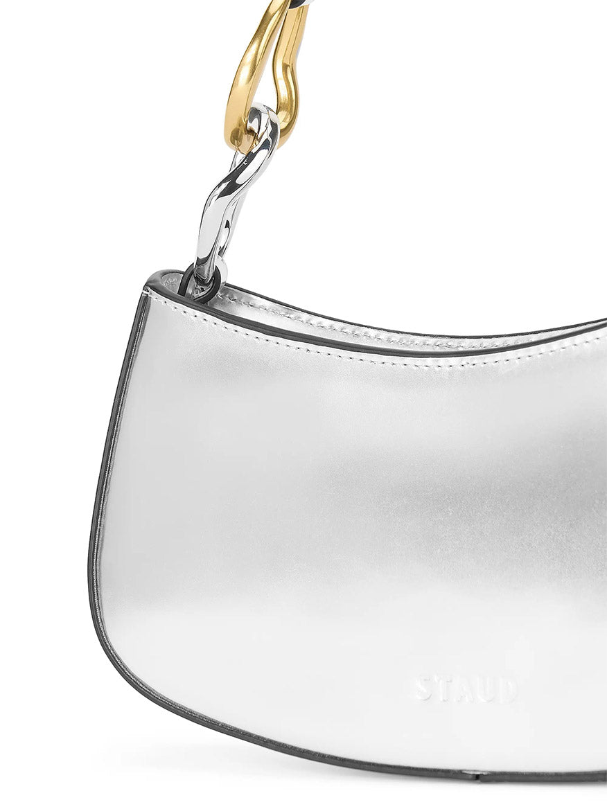 A close-up of the STAUD Ollie Bag in Chrome, a silver mini shoulder bag featuring a two-tone chain strap with gold and silver links.