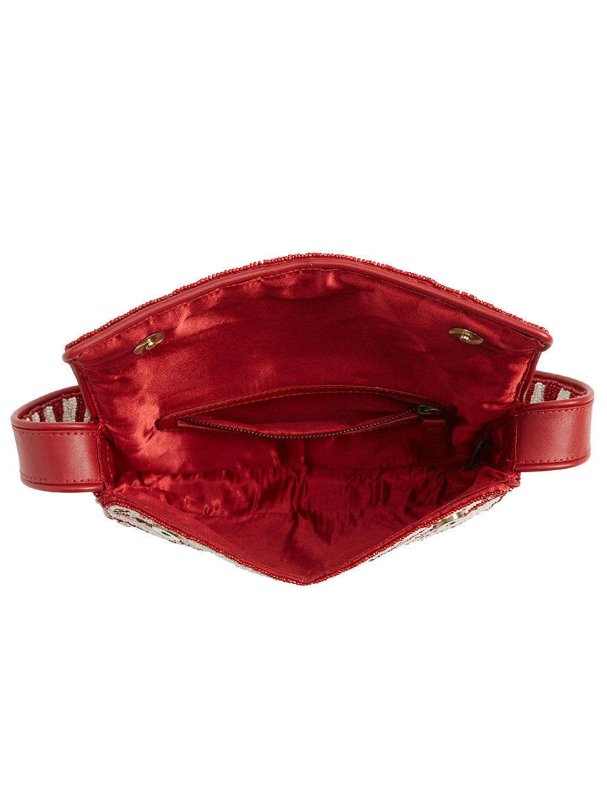 The STAUD Tommy Beaded Bag in Scarlet/White Zebra is shown open with the flap lifted, revealing a red satin interior with a zippered pocket and two snap closures.