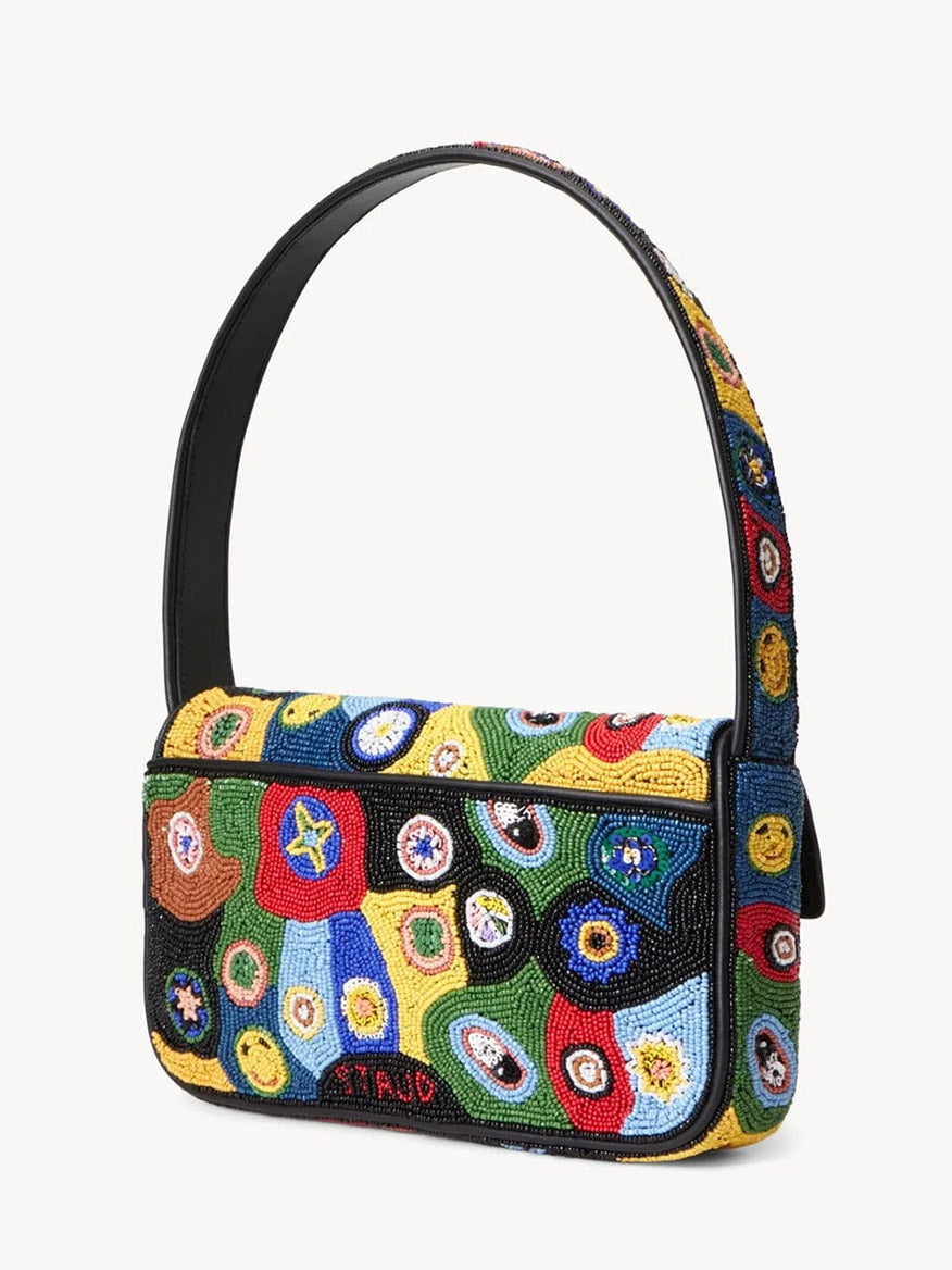 The STAUD Tommy Beaded Bag in Black Millefiori is a rectangular, hand-beaded shoulder bag with a black strap, featuring colorful circular bead patterns on a yellow, green, blue, and black background.