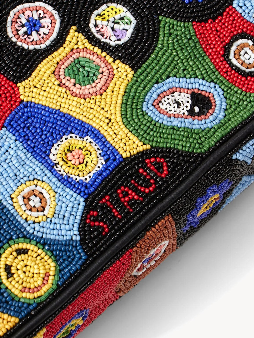 Close-up of the STAUD Tommy Beaded Bag in Black Millefiori, a colorful hand-beaded shoulder bag with circular patterns and "STAUD" beaded in red on a black background.