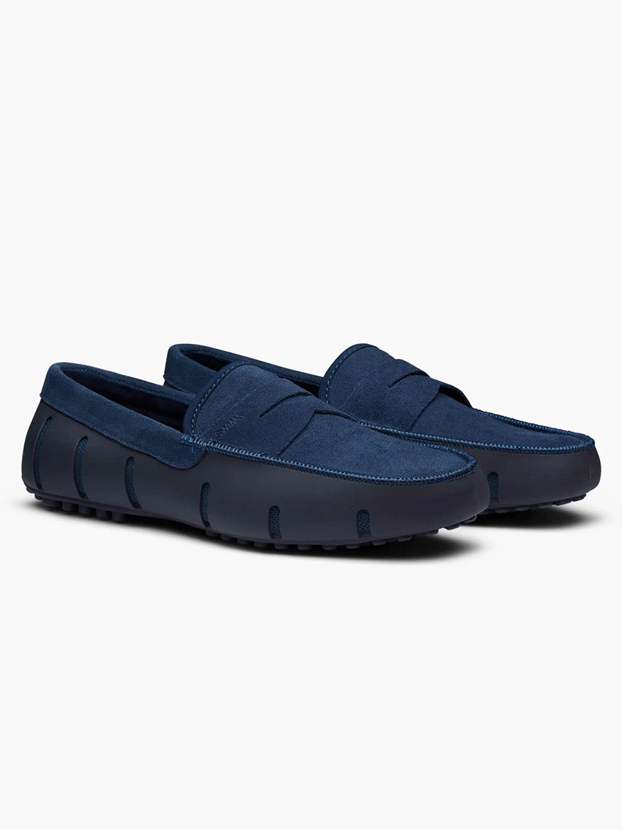 The Swims Lux Driver in Midnight Navy is a pair of suede driver loafers with rubber soles, stitching accents, and an algae-based footbed, shown against a plain white background.