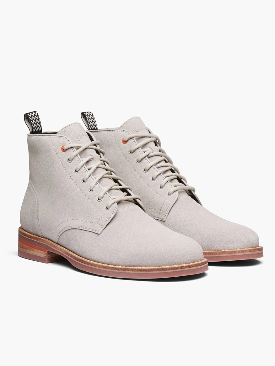 The Swims Oslo Boot in Mist is a pair of light gray waterproof ankle boots with brown soles, featuring black-and-white patterned heel tabs. Crafted from fine Italian leather, they are displayed on a plain white background.