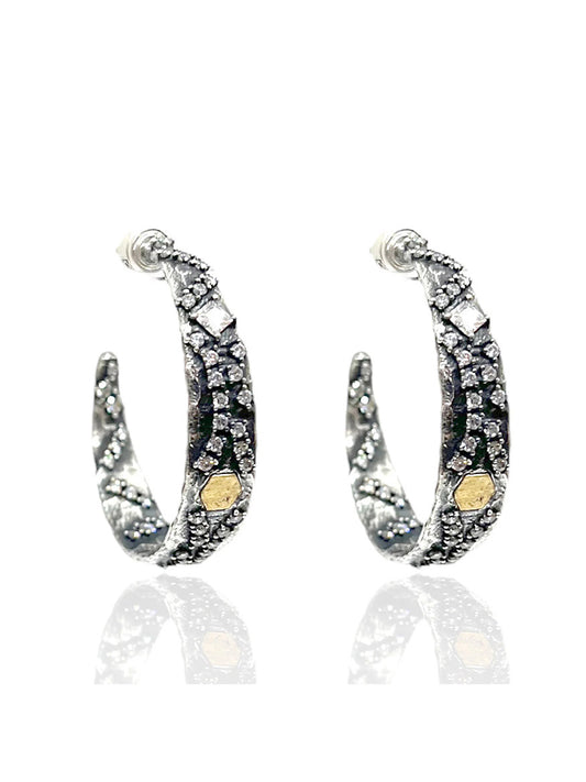 The Tat2 Designs Cosa Hoops in Vintage Silver & Gold feature embedded clear and black stones, gold hexagonal accents, and unique finishes inspired by the Tat2 Prince Collection.