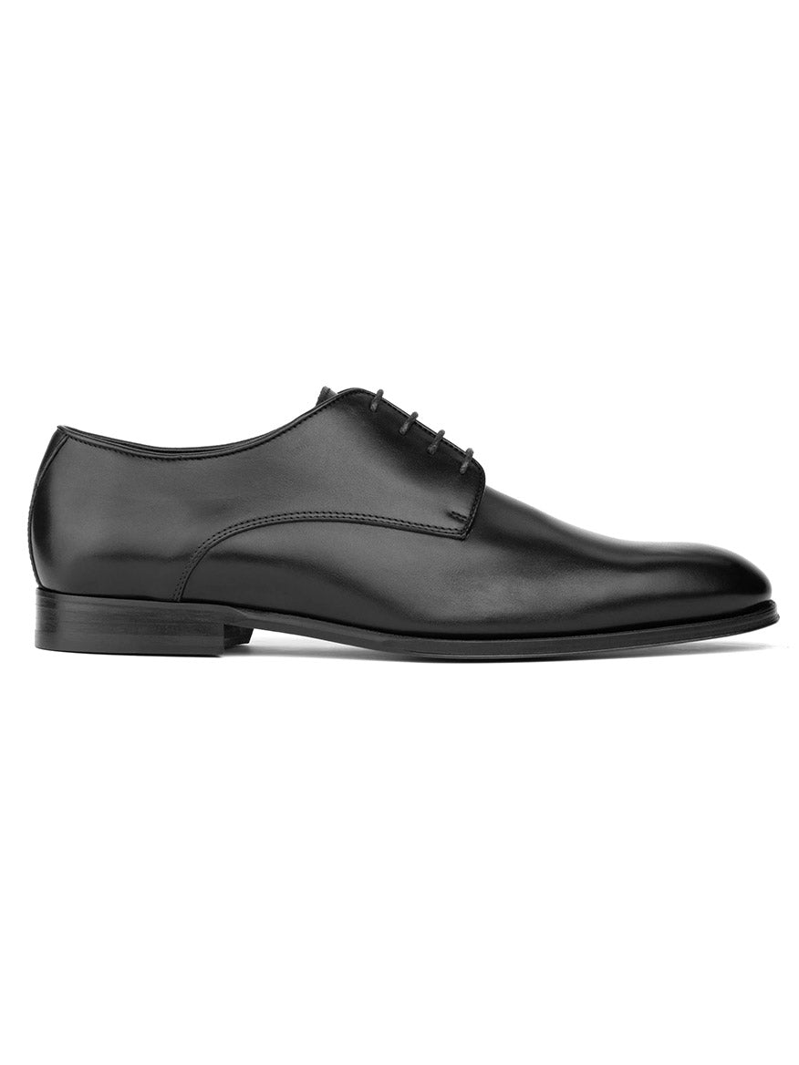 The To Boot New York Blakeley in Black is a polished black leather dress shoe, crafted from luxurious Italian calfskin. It boasts a sleek finish and a low heel, showcasing a classic oxford silhouette and leather sole when viewed from the side.
