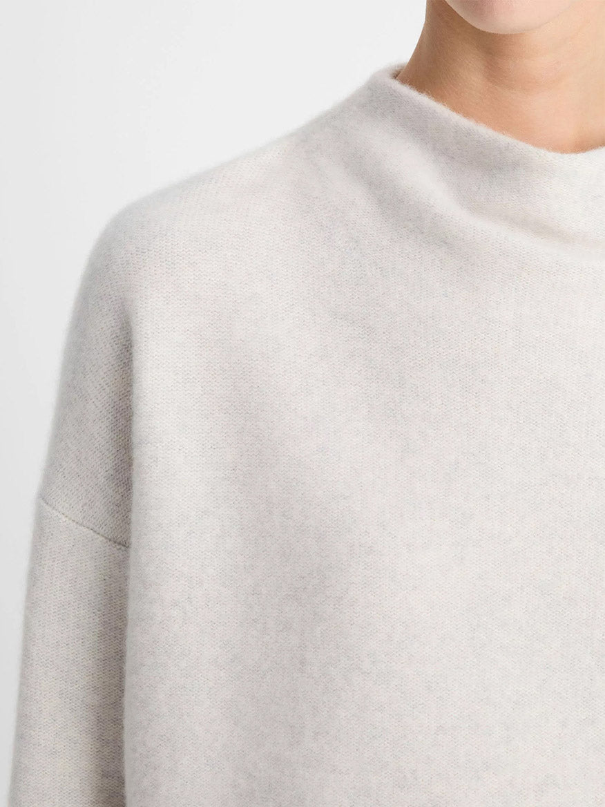 A person wears the Vince Plush Cashmere Funnel-Neck Sweater in Heather Platinum, shown from the shoulders up against a plain background.