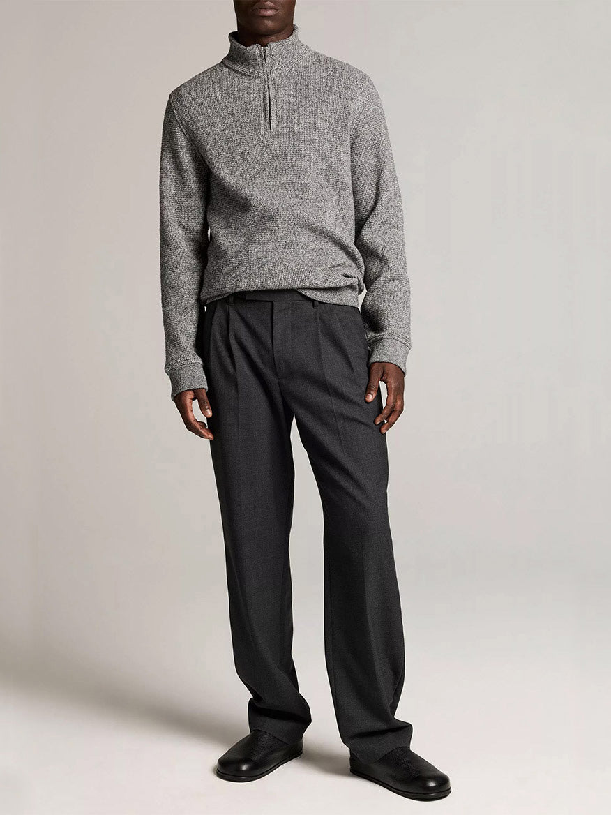 A person wears the Vince Brushed Cotton-Blend Waffle Quarter-Zip Pullover in Heather Black, paired with dark pleated trousers and black shoes against a plain light background.