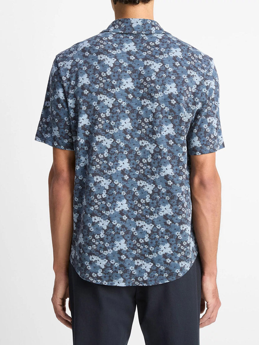 A person wearing the Vince Floral Slub Cotton Short-Sleeve Button-Front Shirt in Coastal Blue is seen from the back against a plain white background.