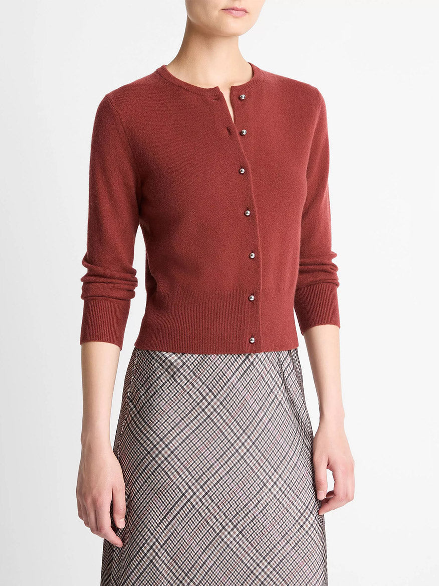 A person wears a Vince Metal-Button Wool & Cashmere-Blend Cardigan in Siena and a plaid, high-waisted skirt.