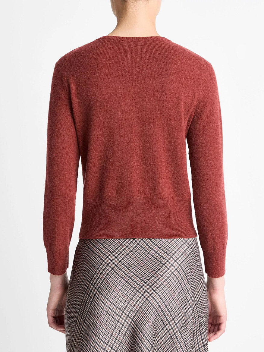A person is shown from behind wearing the Vince Metal-Button Wool & Cashmere-Blend Cardigan in Siena, paired with a plaid skirt.