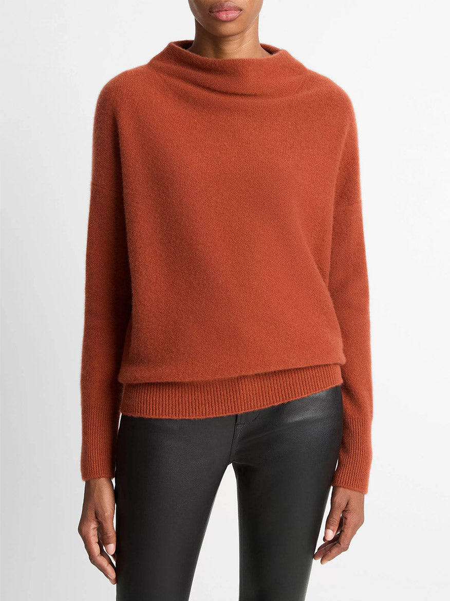 A person wears the Vince Plush Cashmere Funnel-Neck Sweater in Tuscan Red with black leather pants against a plain white background.