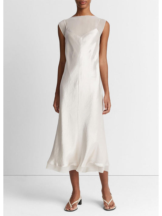A woman wearing a Vince Chiffon-Layered Satin Slip Dress in Champagne with white sandals stands against a neutral background.