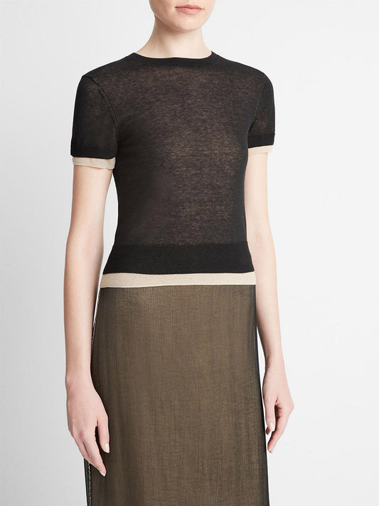 A woman wearing a stylish black Vince Double Layer Knit T-Shirt with a white hemline, paired with a long olive-green fine gauge-knit skirt.
