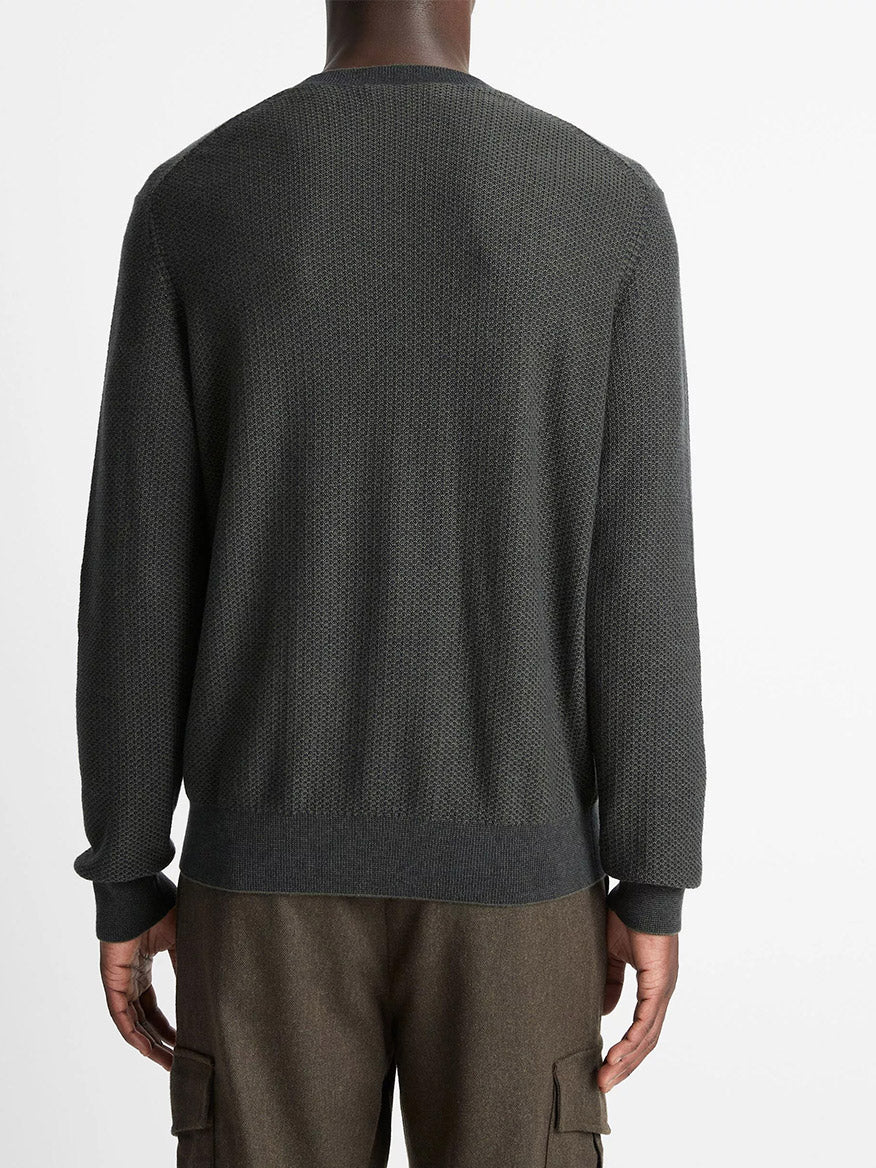 A person wearing the Vince Geo-Jacquard Wool-Blend Crew Neck Sweater in Driver Green/Coastal Blue and brown cargo pants stands facing away from the camera against a plain white background.