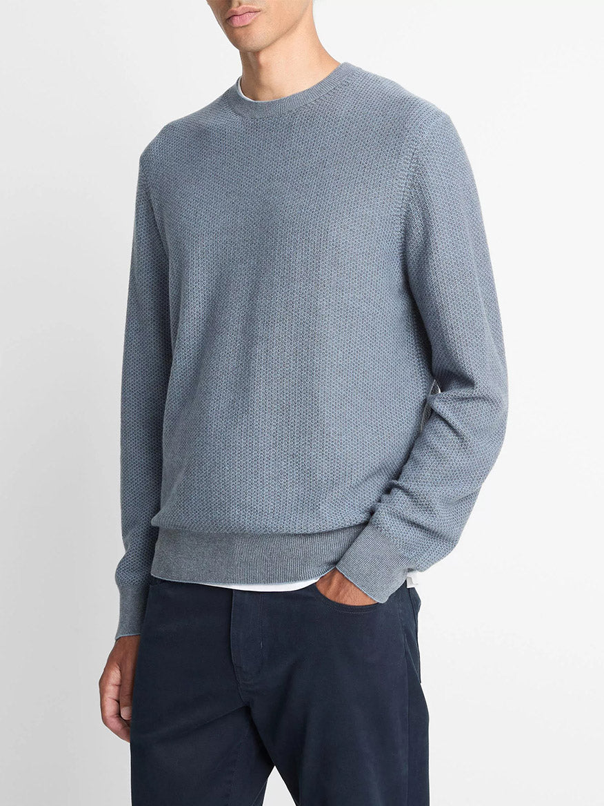 A person wears the Vince Geo-Jacquard Wool-Blend Crew Neck Sweater in Parlor Blue/Medium Heather Grey over a white shirt and dark blue pants, standing against a plain white background.