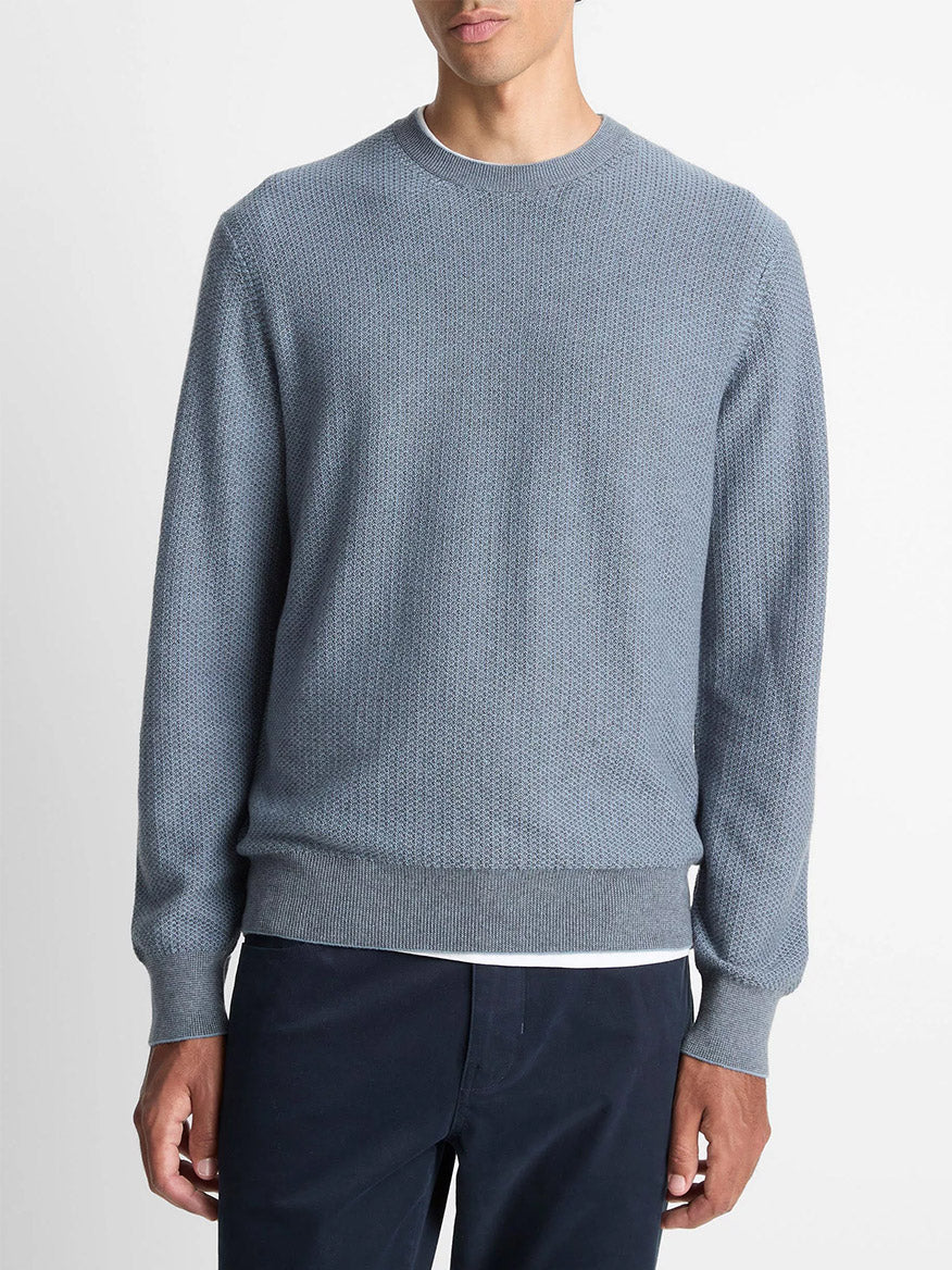 A person wearing the Vince Geo-Jacquard Wool-Blend Crew Neck Sweater in Parlor Blue/Medium Heather Grey with dark pants stands against a plain white background.