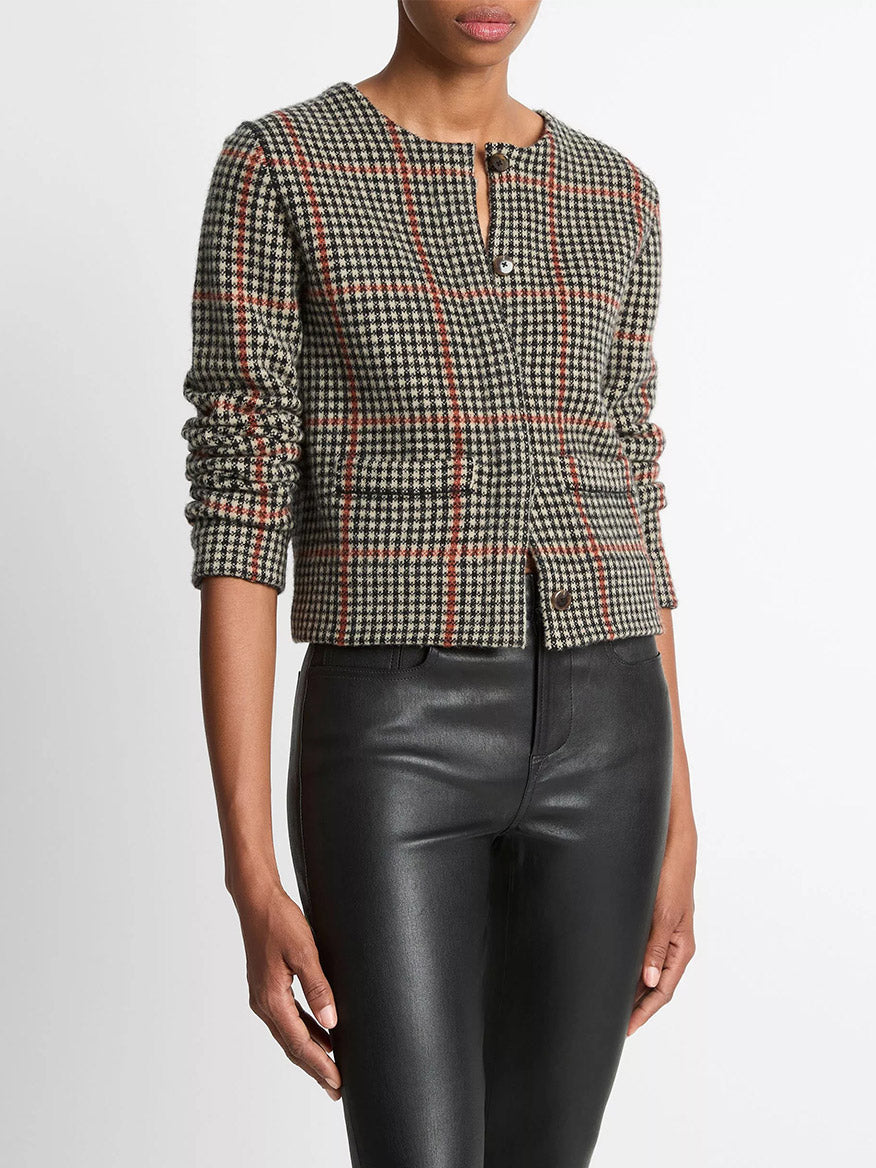 A person wearing the Vince Glen Plaid Wool-Cashmere Cardigan Jacket in Cobblestone/Black Combo, styled with high-waisted black leather pants.