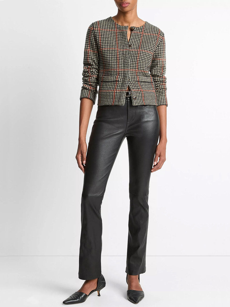 A person wearing the Vince Glen Plaid Wool-Cashmere Cardigan Jacket in Cobblestone/Black Combo, black leather pants, and black pointed-toe heels stands against a plain white background.