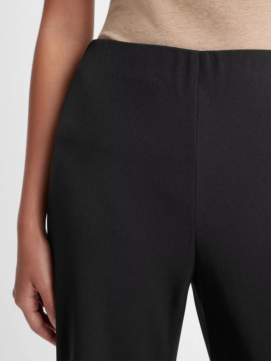 A person wearing a beige top and Vince High-Waist Crepe Bias Pant in Black, featuring a hidden elastic waistband, is shown from waist to mid-thigh with one arm visible at the side.