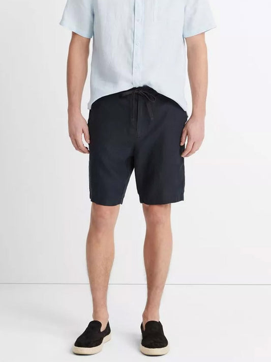 Man wearing a light blue short-sleeved shirt, and Vince Lightweight Hemp Short in Coastal with drawstring closure, paired with dark shoes.