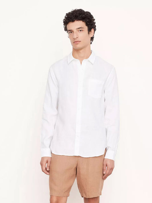 Answer: Man in a Vince Linen Long Sleeve Shirt in Optic White and beige shorts standing against a light background.