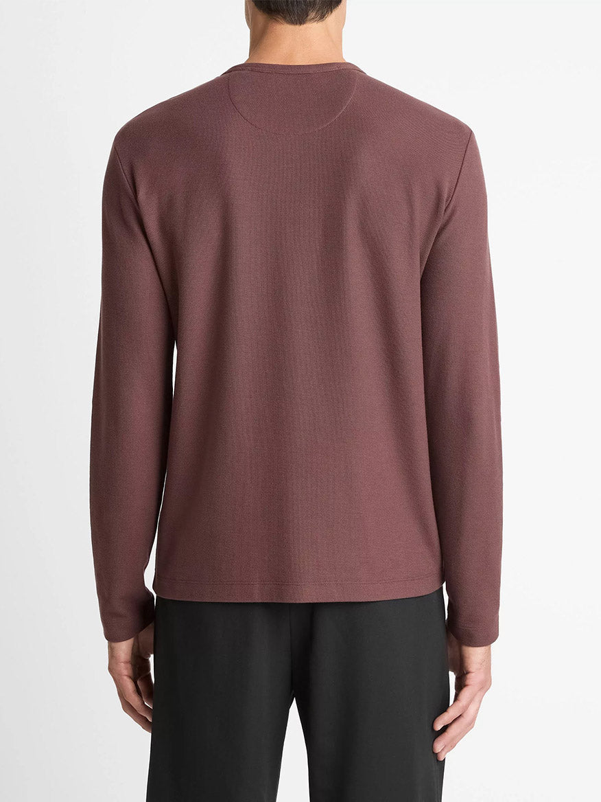 A person is shown from the back wearing the Vince Pima Cotton Piqué Long-Sleeve T-Shirt in Washed Port and black pants, set against a plain white background.