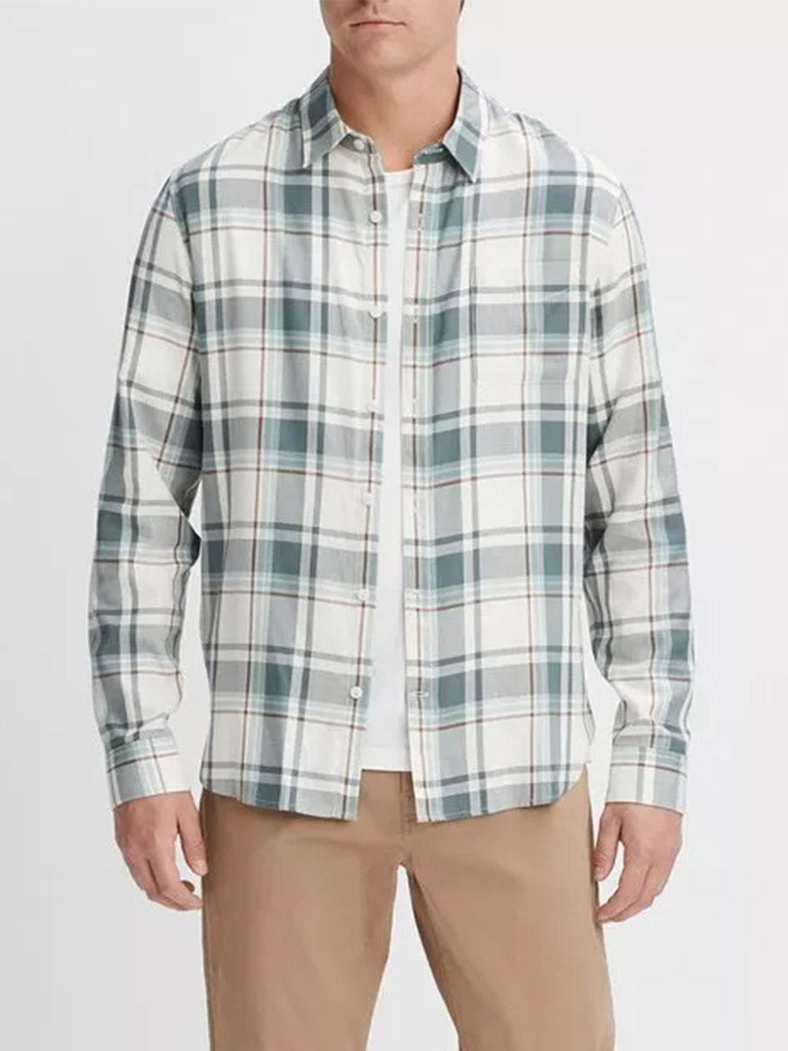 A man wearing a Vince Manchester Plaid Shirt in Bone/Dusty Teal with shades of white, blue, and green. He is also wearing beige pants. The cotton-blend shirt is untucked.