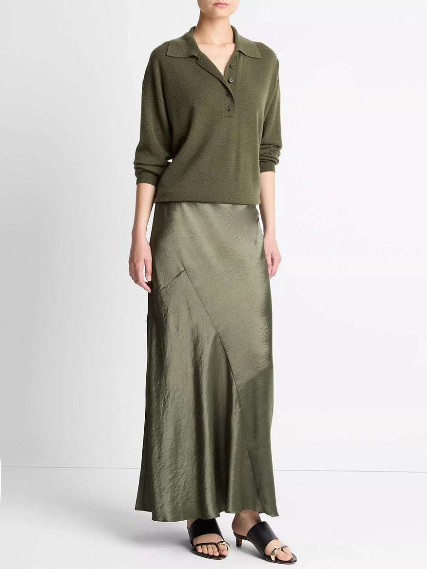 Person wearing a Vince olive green long-sleeve top, a Vince Paneled Satin Bias Skirt in Herba, and black sandals, standing against a plain white background.