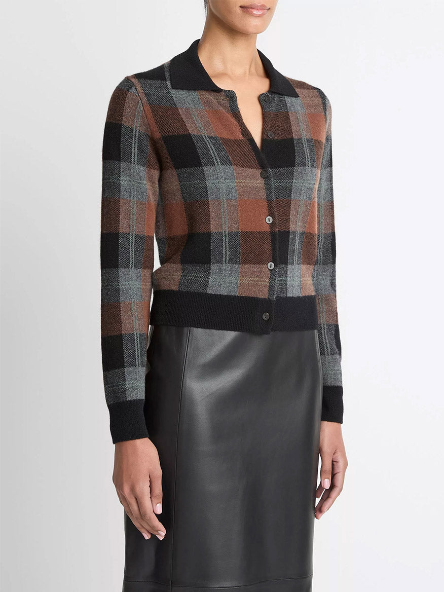 A person wearing the Vince Checked Plaid Cashmere Polo Cardigan in Cacao/Dark Heather Pewter/Black with a black leather skirt.